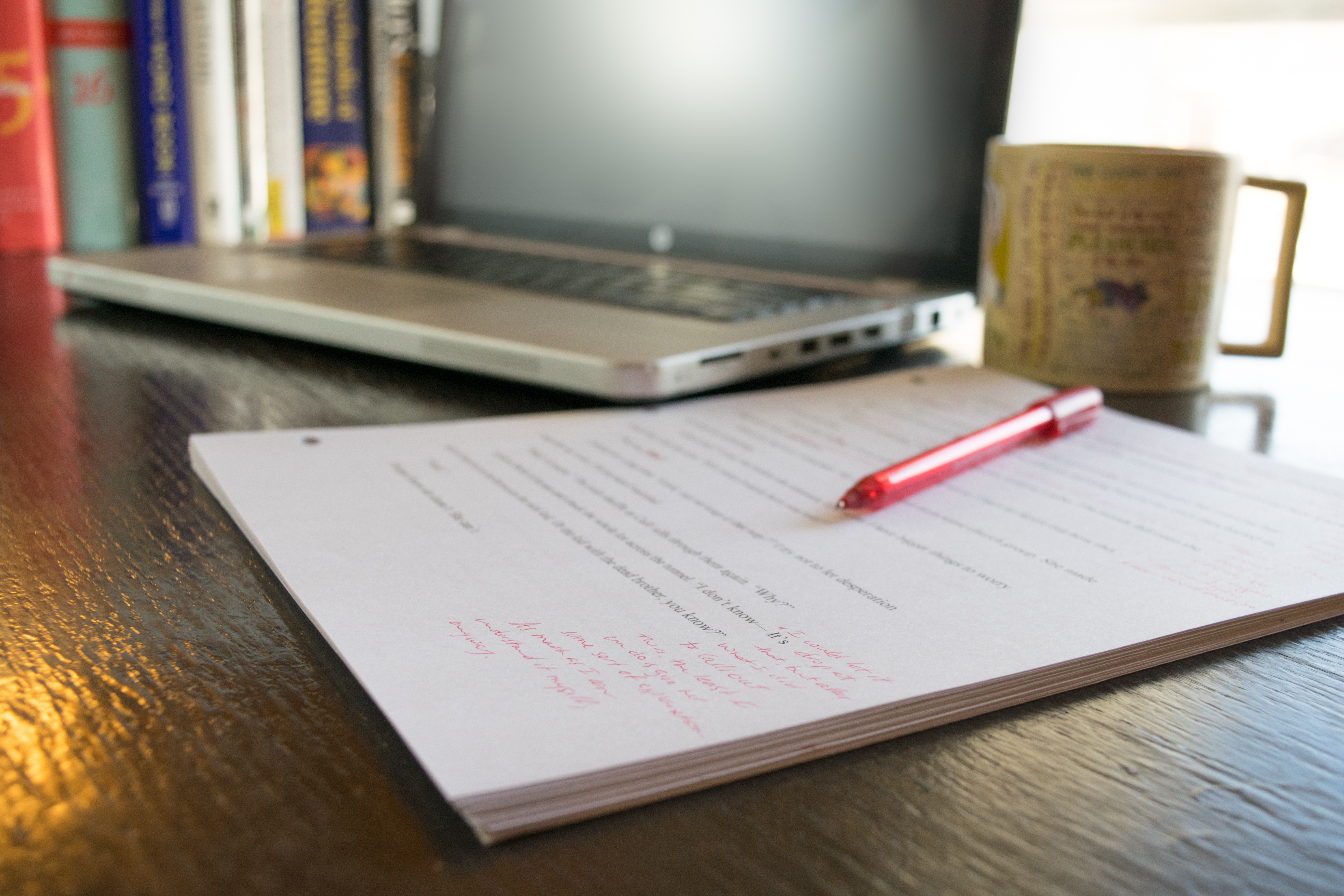 Office Desk with marked up paper computer, coffee, and red pen