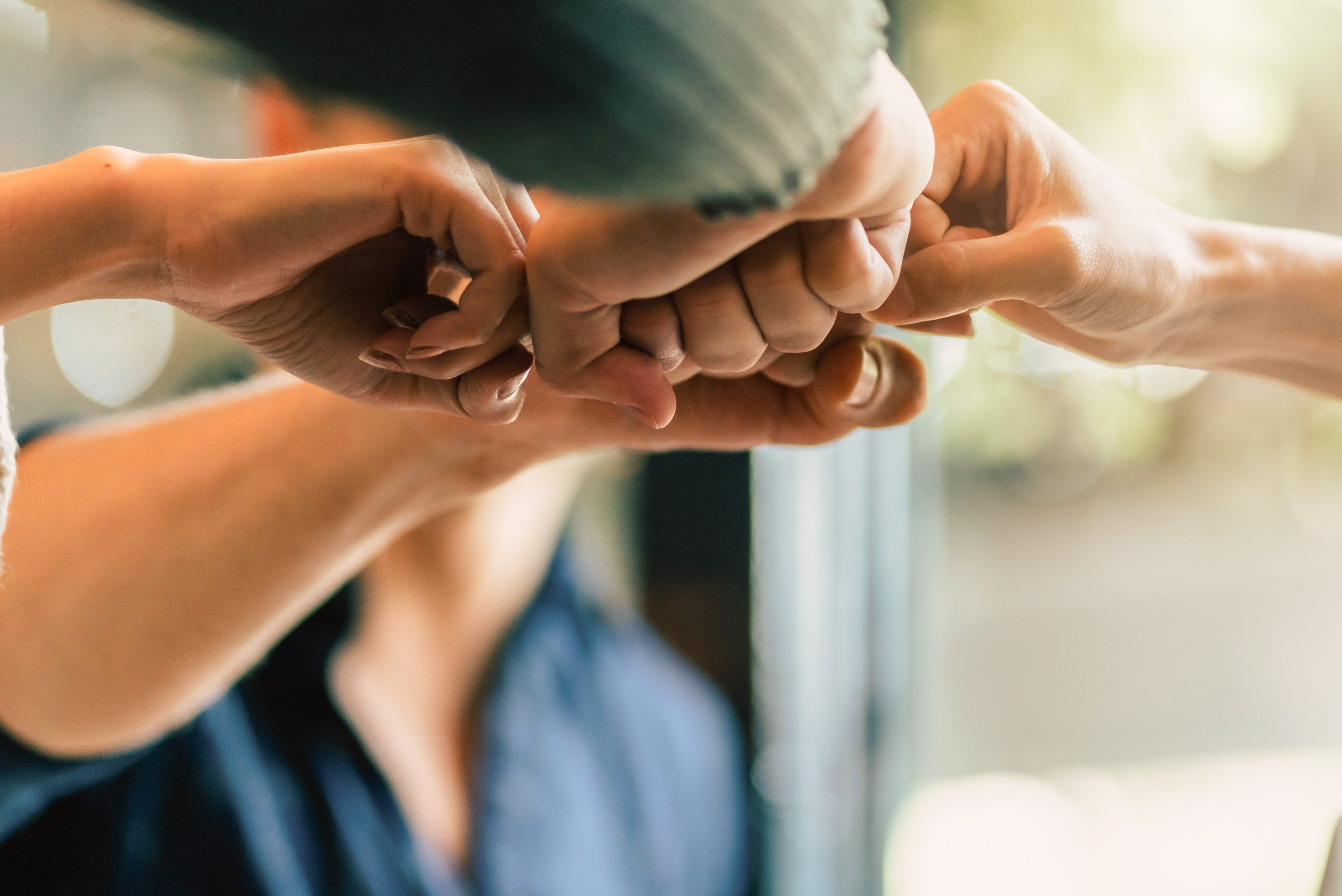 Team of people putting their fists together in victory.